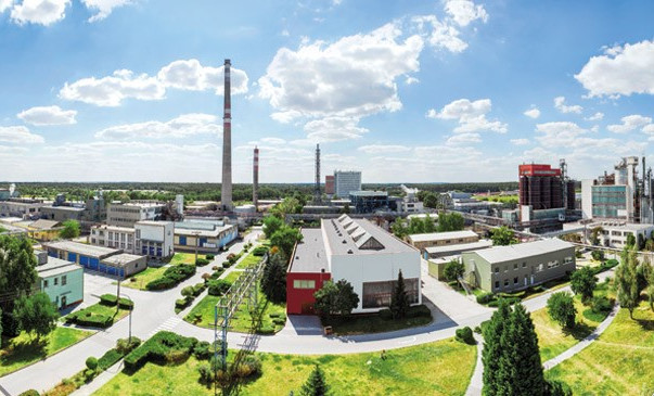 Panoramatický pohled na průmyslový areál s továrnami, komíny a zelenými plochami
