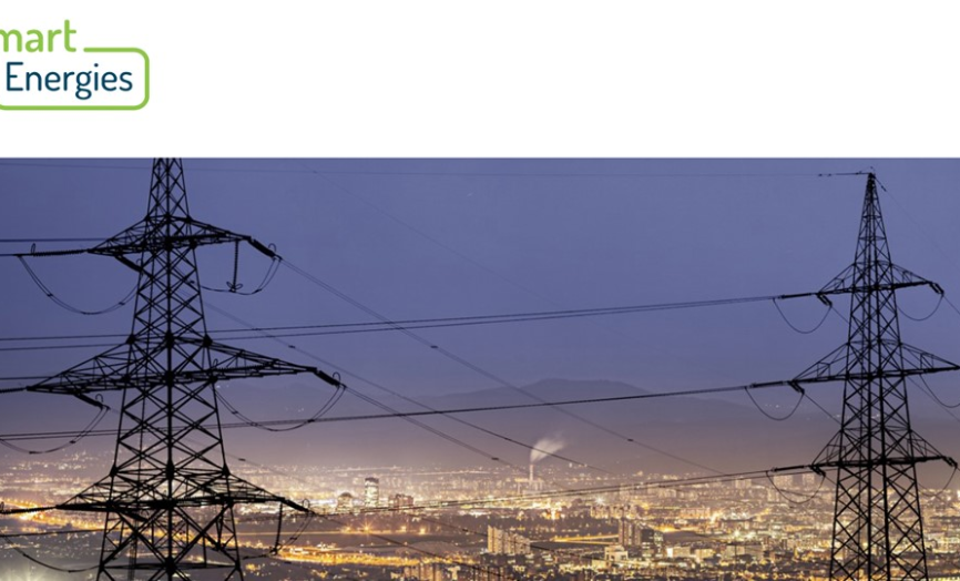 Vysoké elektrické vedení s dvojicí přenosových stožárů v popředí a večerním panoramatem města v pozadí, doplněné logem Smart Energies v horní části obrázku.