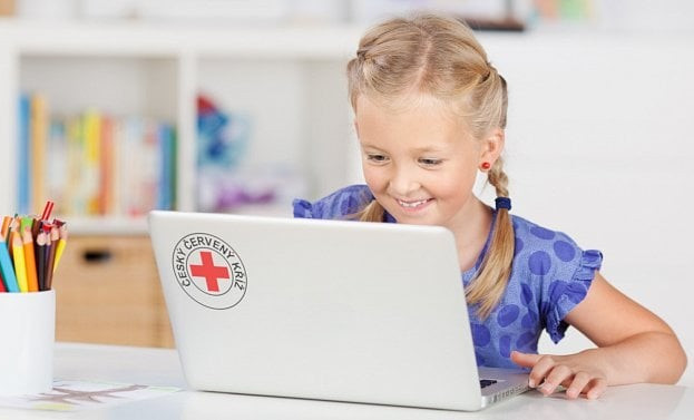 Dívka u počítače s logem Českého červeného kříže sedí u stolu a usmívá se při práci