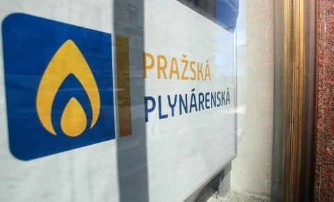 Logo Pražská plynárenská na skle budovy s modro-žlutým symbolem plamene.